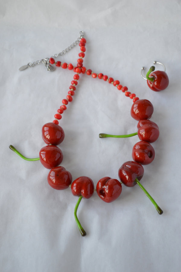 Necklace and earrings made of red beads and green stems on a white background