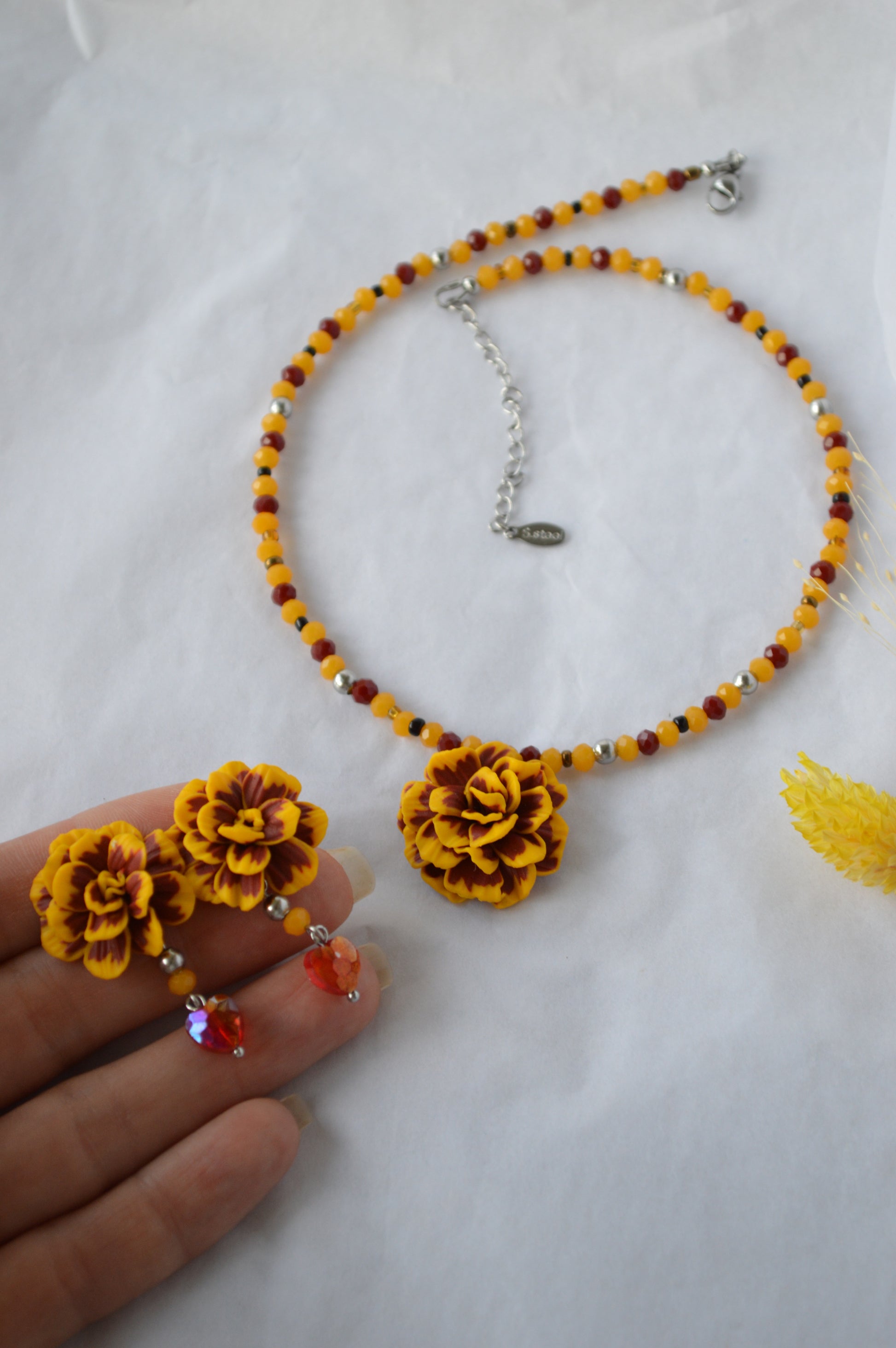 Necklace with yellow floral pendants and beads on a white background