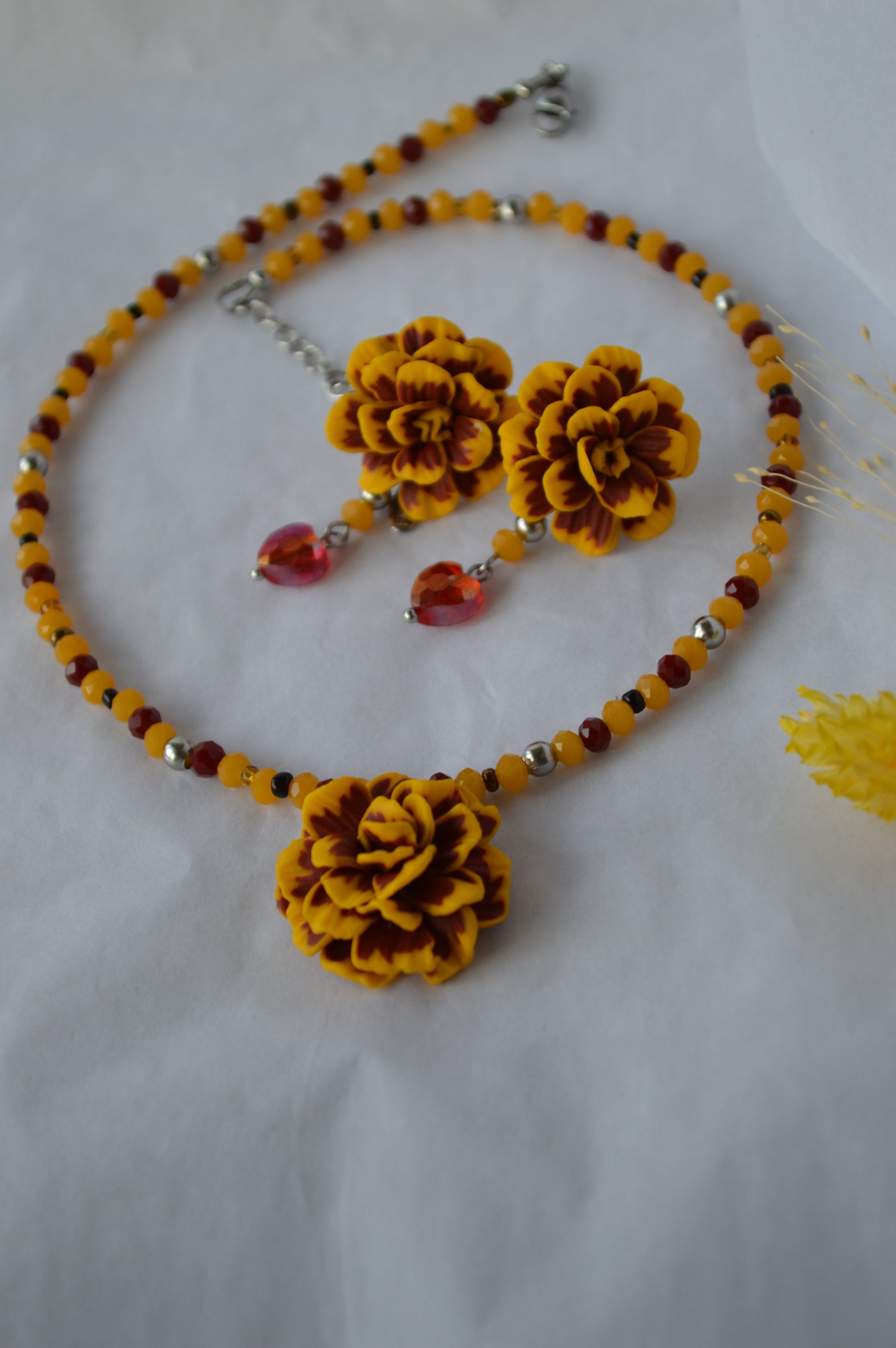 Jewelry set with yellow floral beads and red accents on a white background