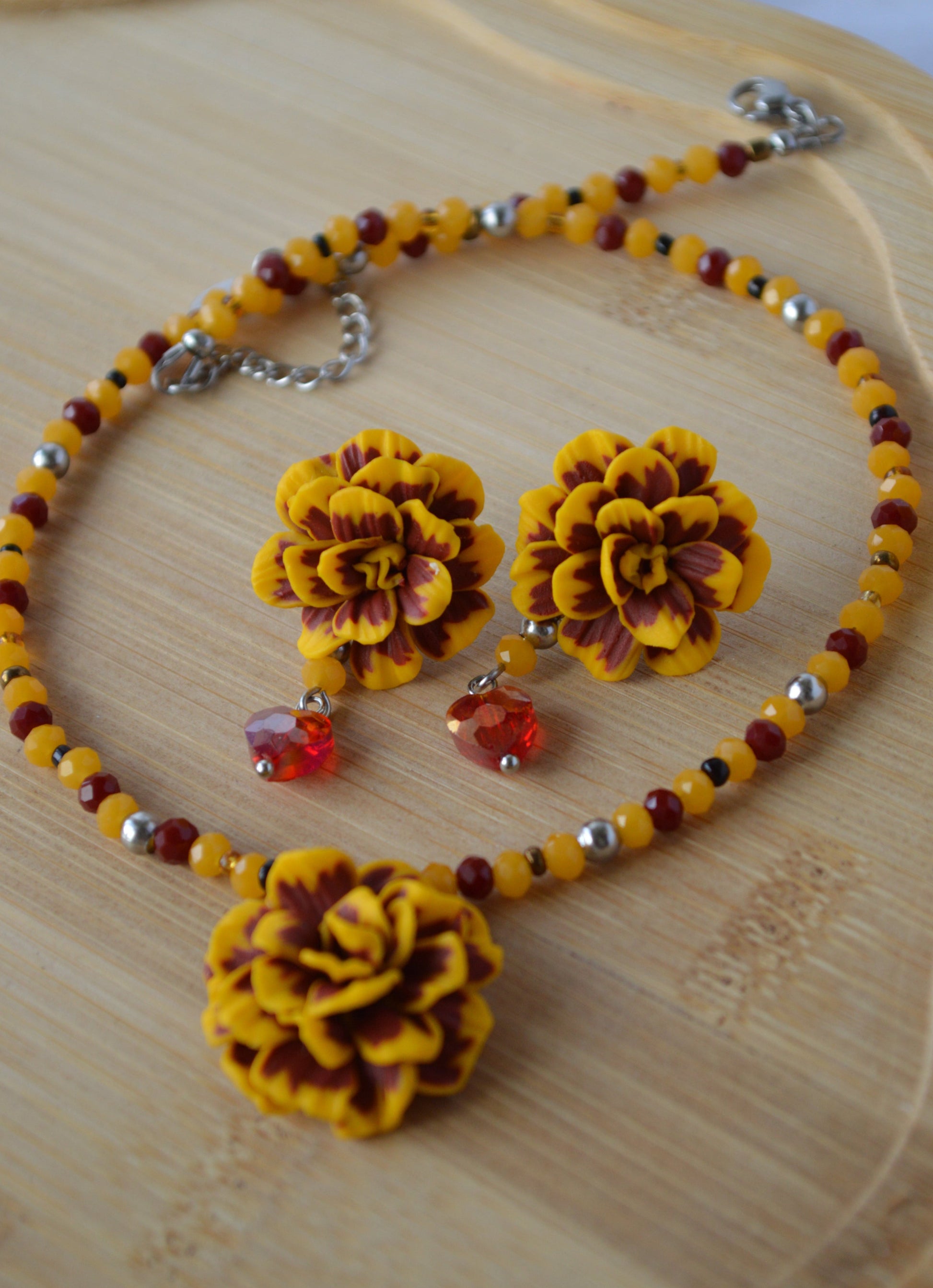 Jewelry set with yellow floral earrings and necklace on a wooden surface