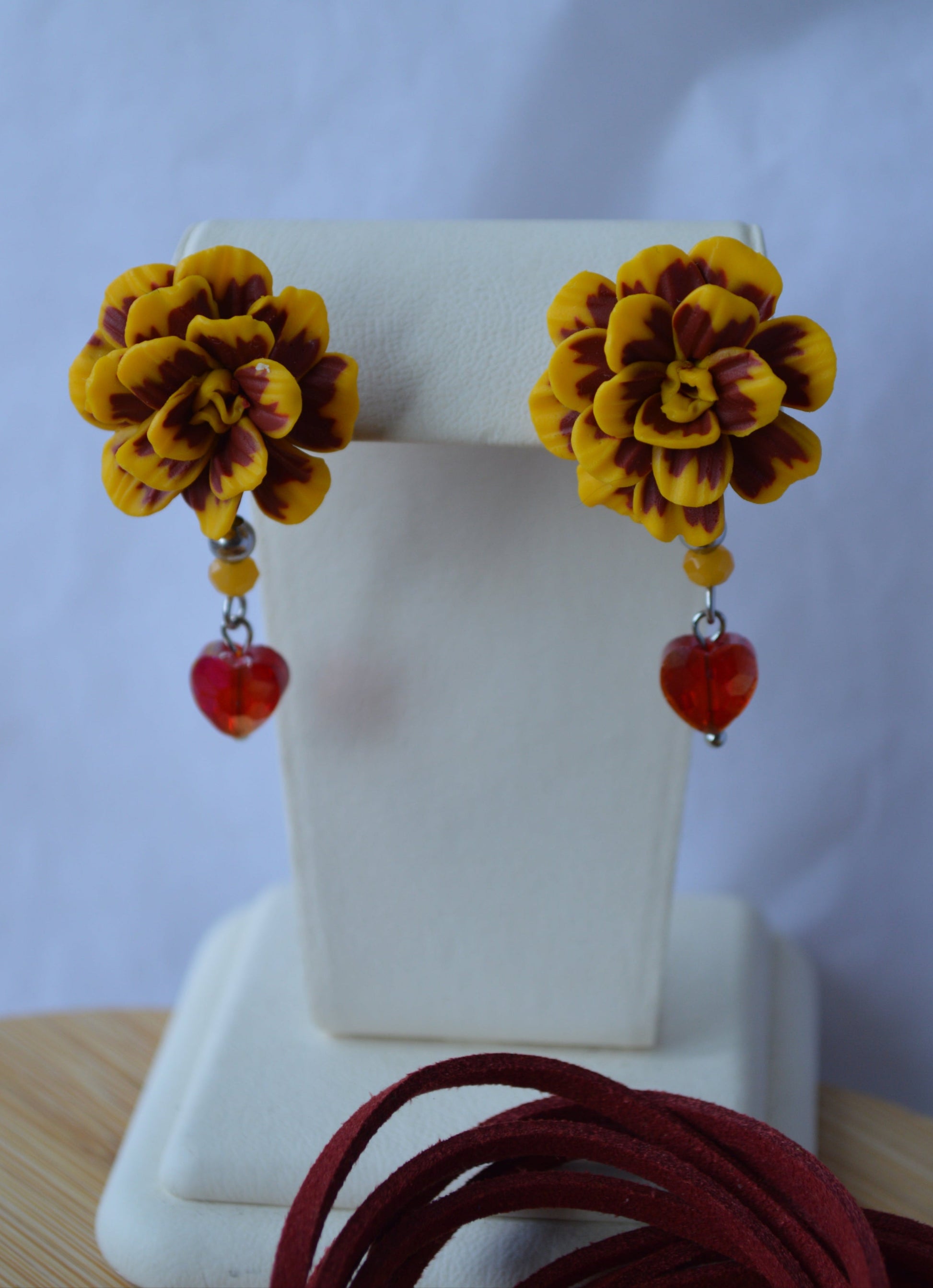 Yellow floral earrings with red accents on a white card against a light blue background