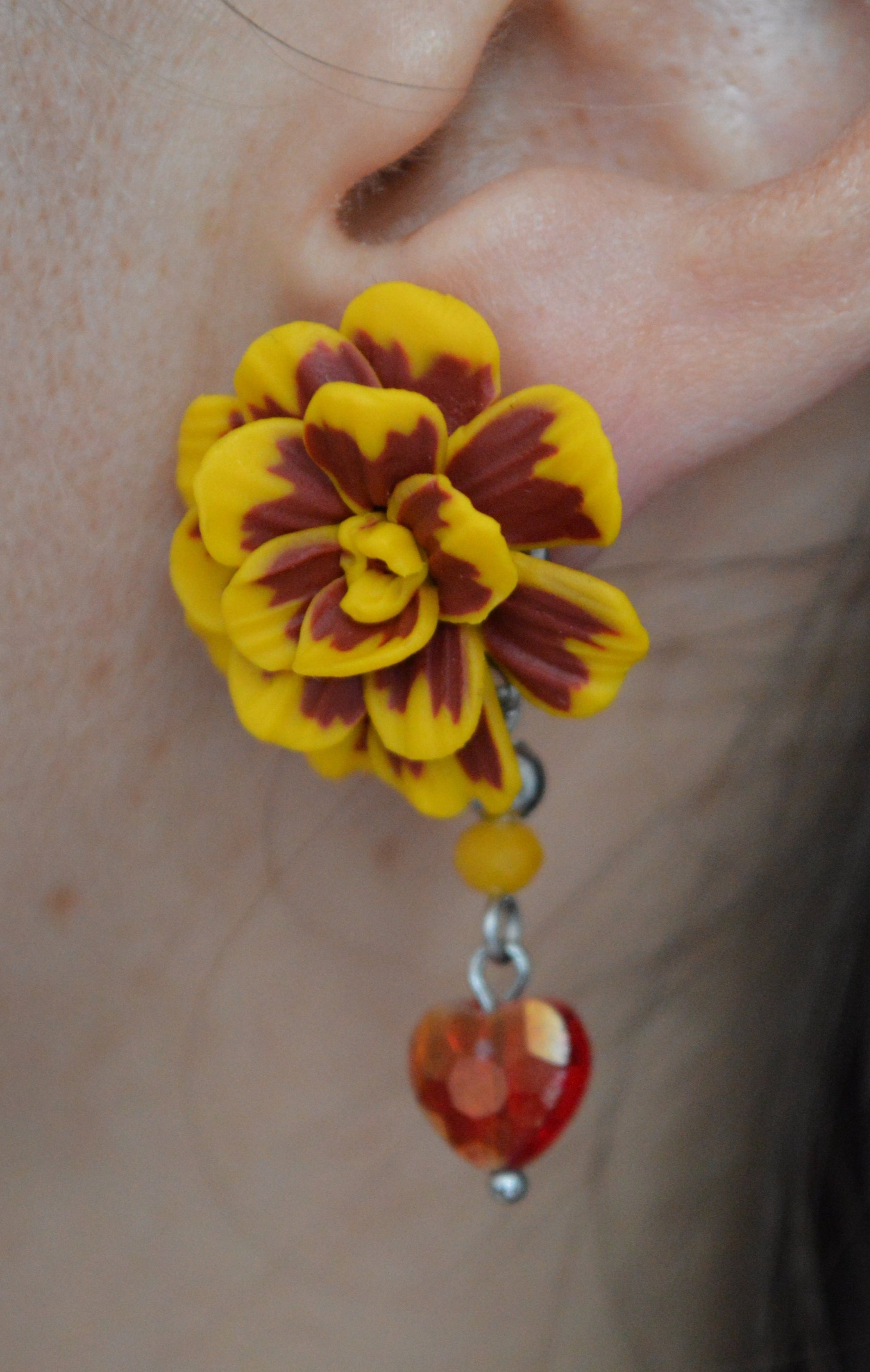 Yellow flower-shaped earring worn on an ear