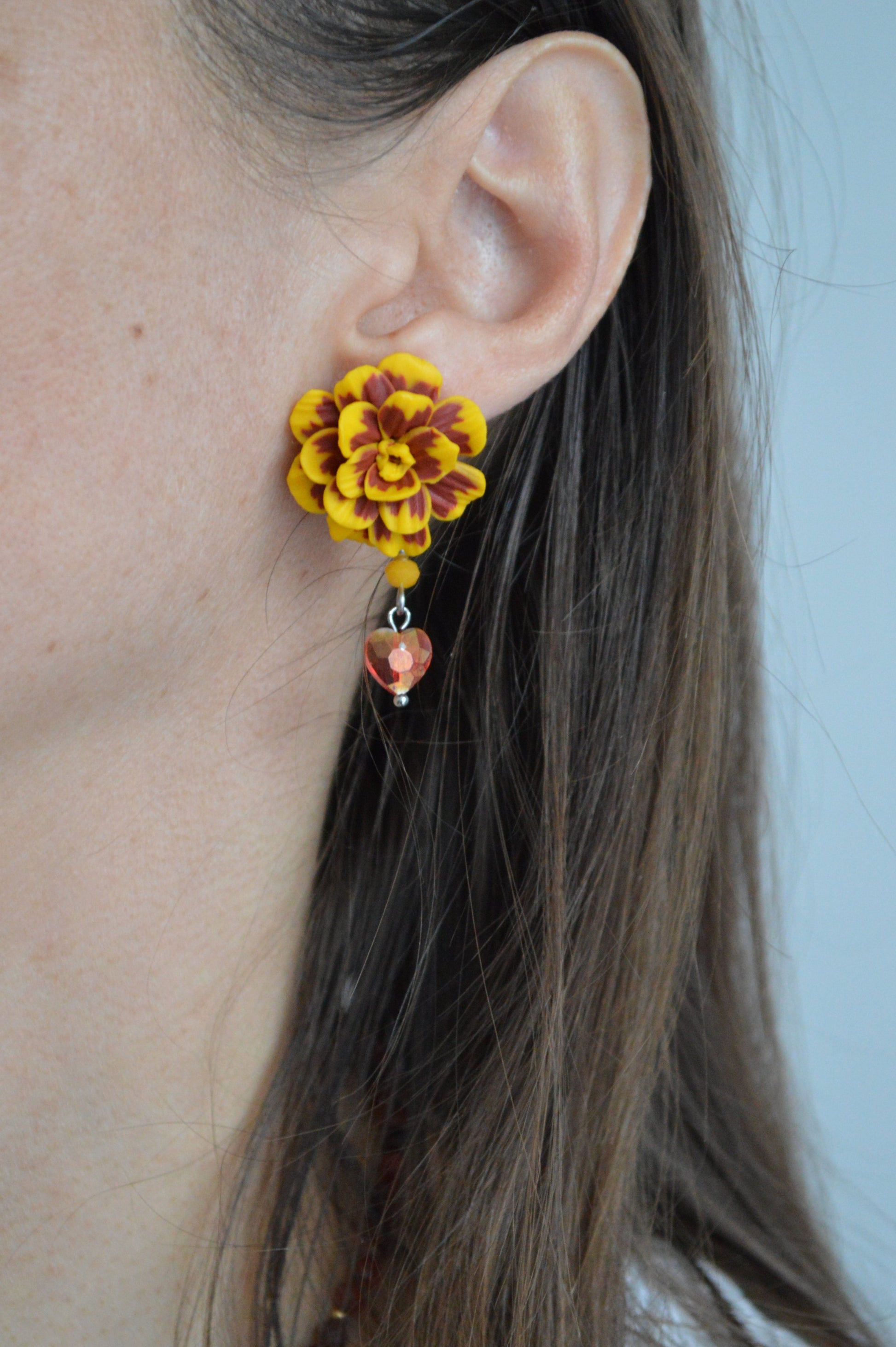 Close-up of an ear with a floral earring on a neutral background