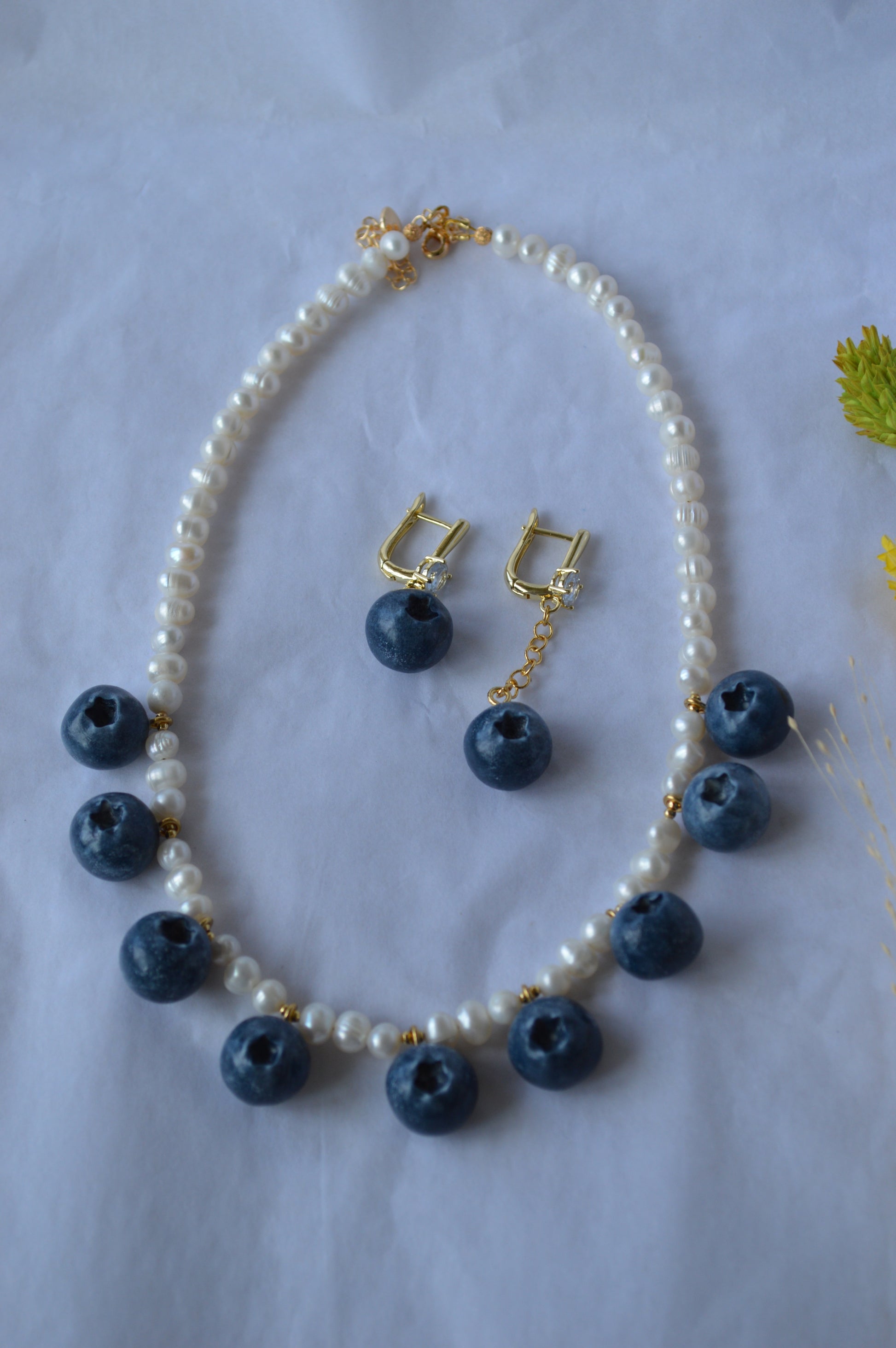 Necklace with blue berry-like beads and matching earrings on a white background