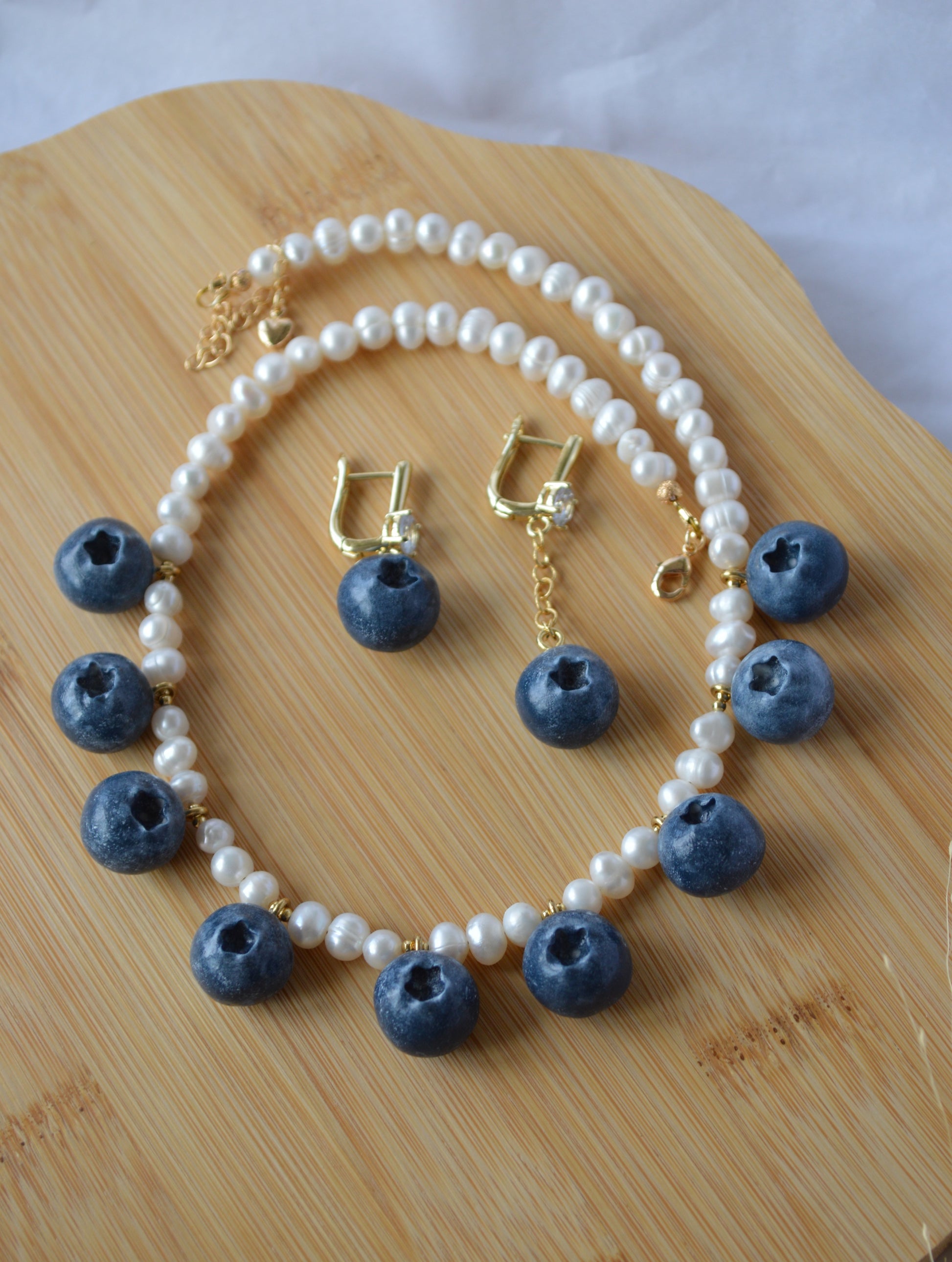 Necklace and earrings with blue berry-like beads on a wooden surface