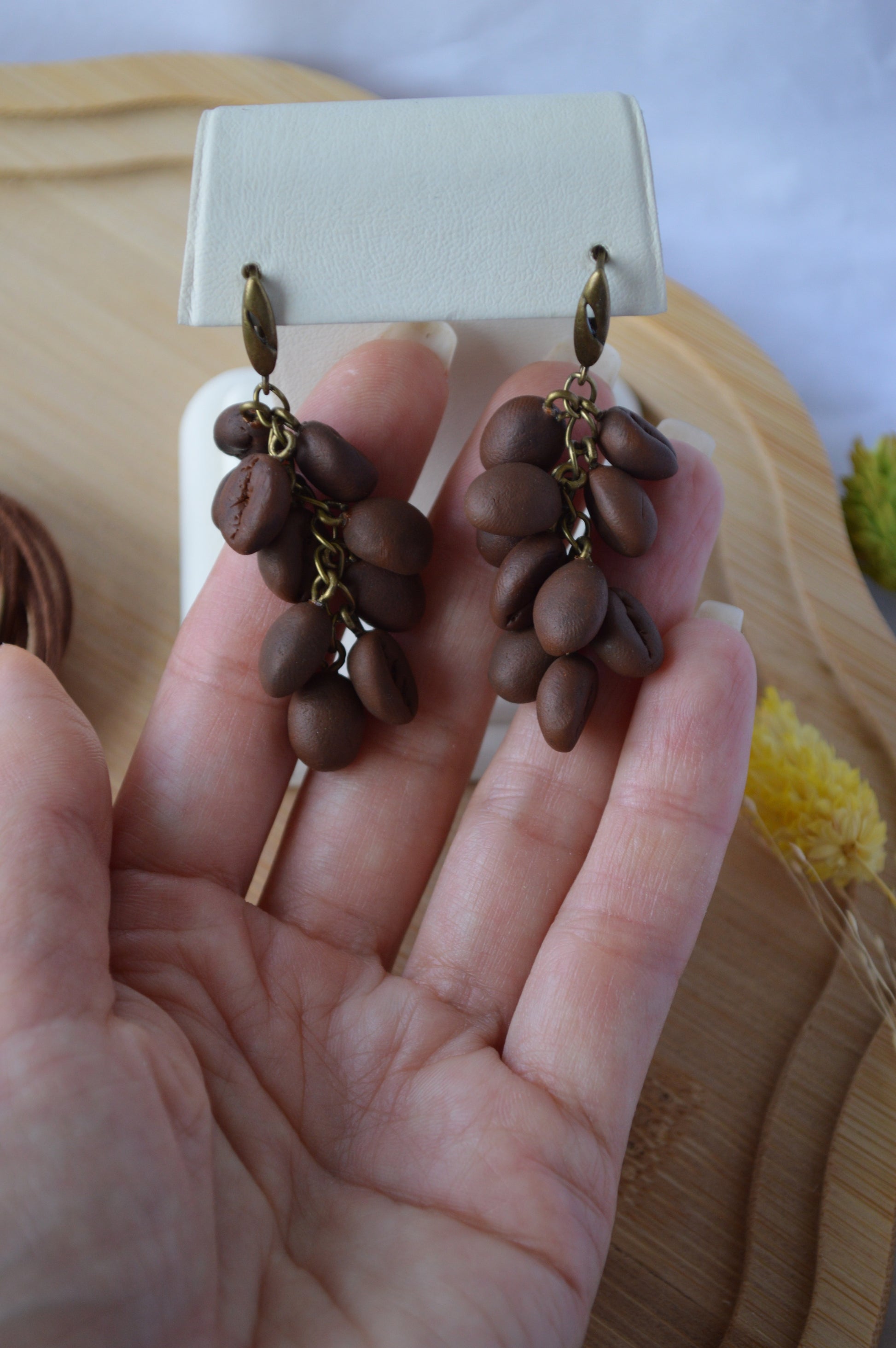 Brown beaded earrings on a hand with a blurred background