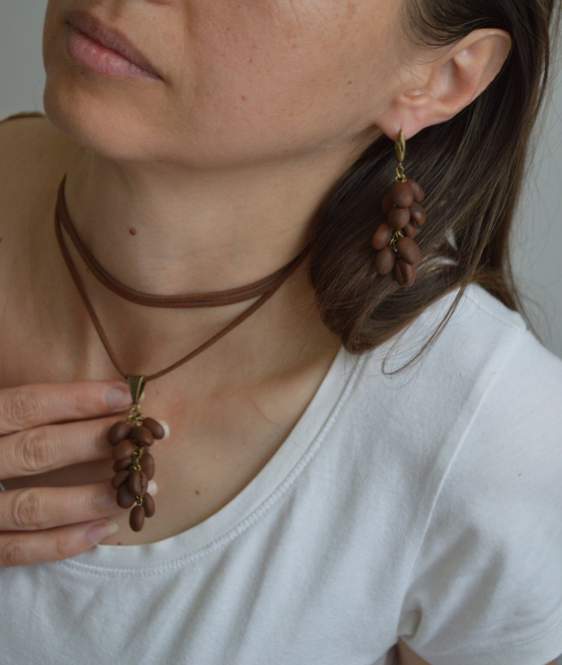 Person wearing a necklace and earrings with coffee bean design