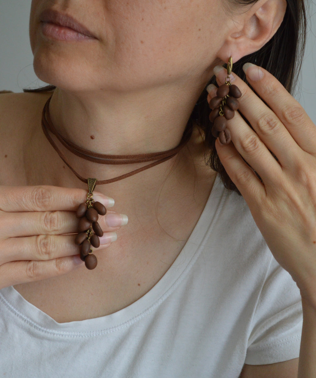 Person wearing a necklace and earrings, with hands adjusting the jewelry.