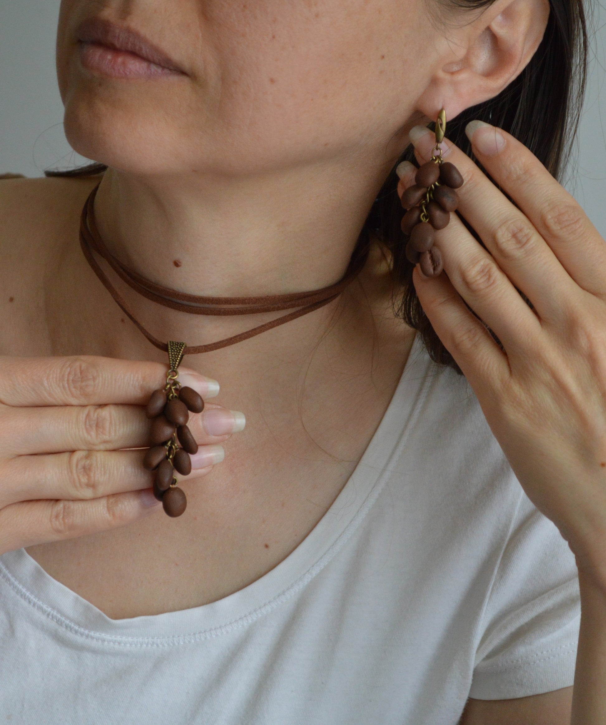 Person wearing a necklace and earrings, with hands adjusting the jewelry.
