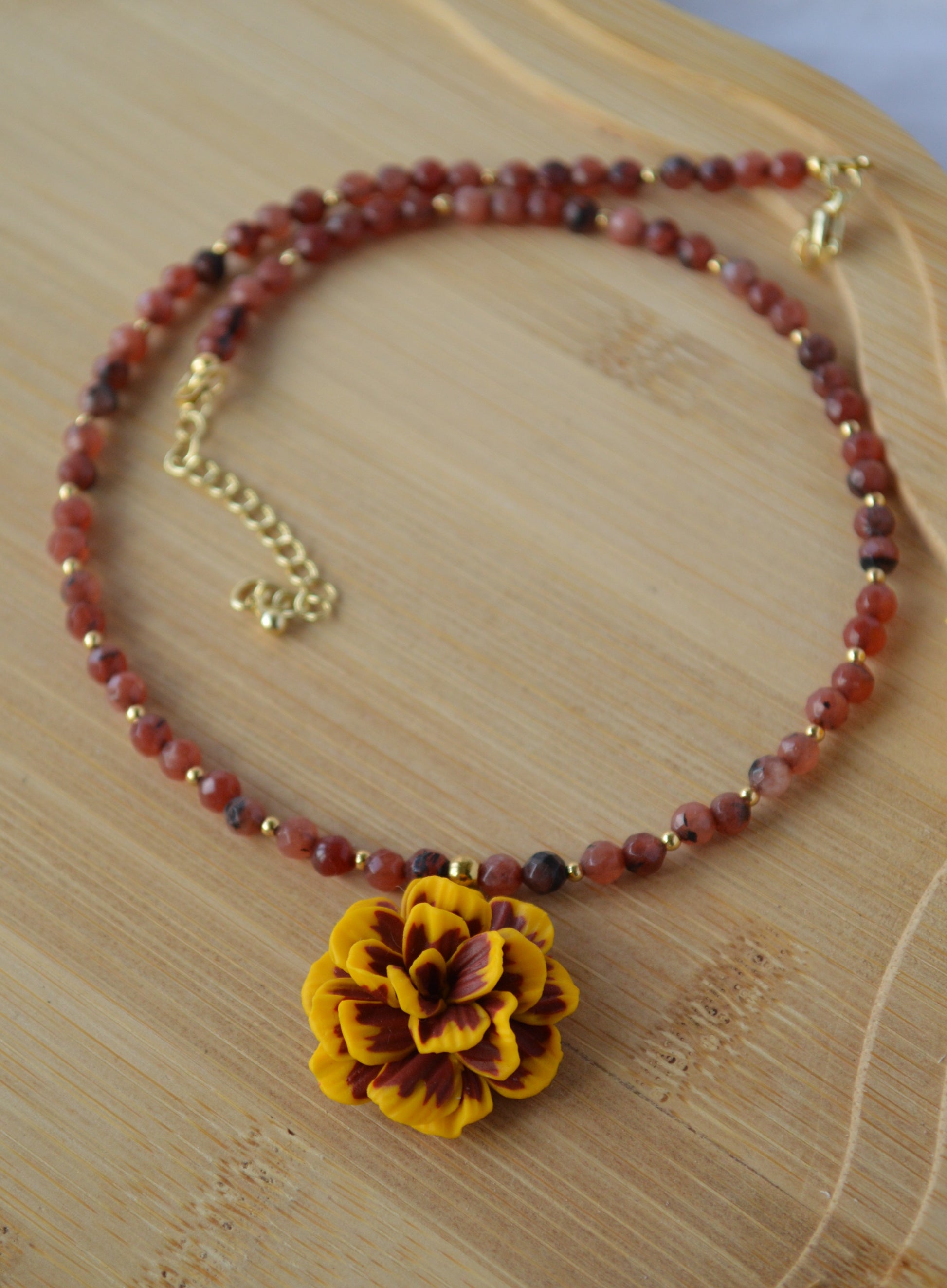Beaded bracelet with a yellow flower charm on a wooden surface