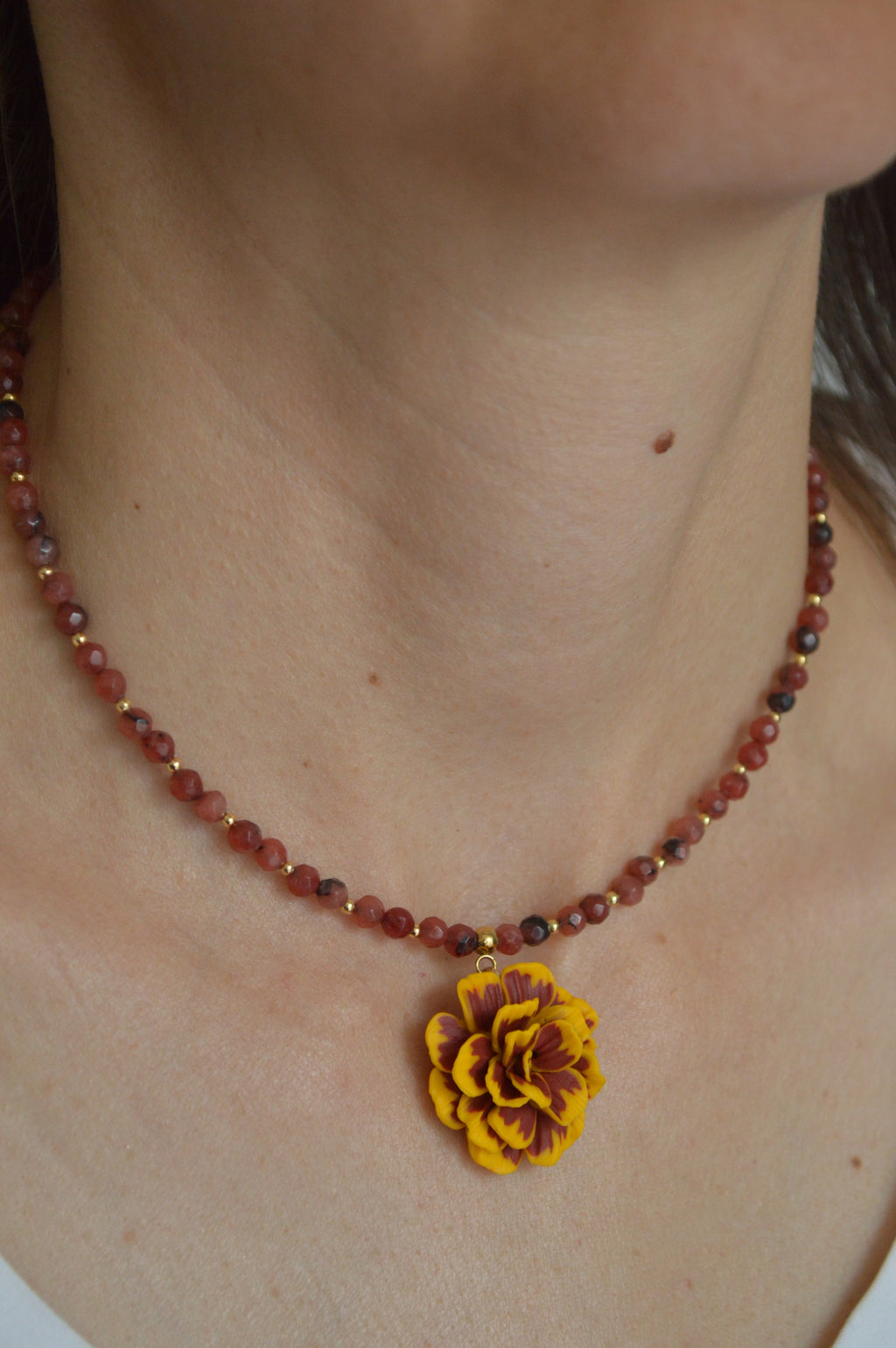 Necklace with a yellow flower pendant on a person's neck