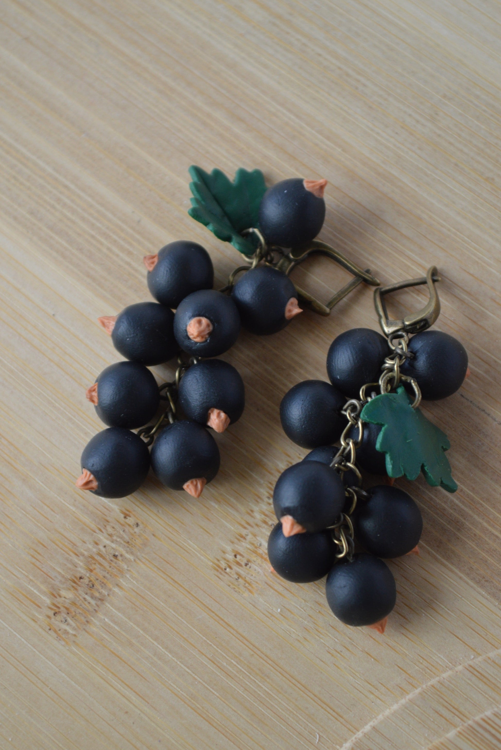 Bracelet with dark blue grape charms on a wooden surface